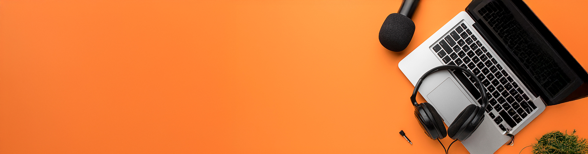 Audio gear including a microphone and headphones on an orange background